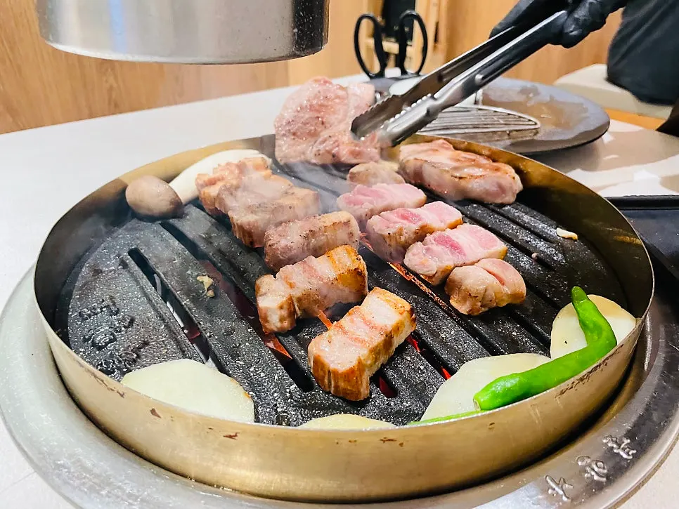 불판 위에서 익어가는 목살과 채소