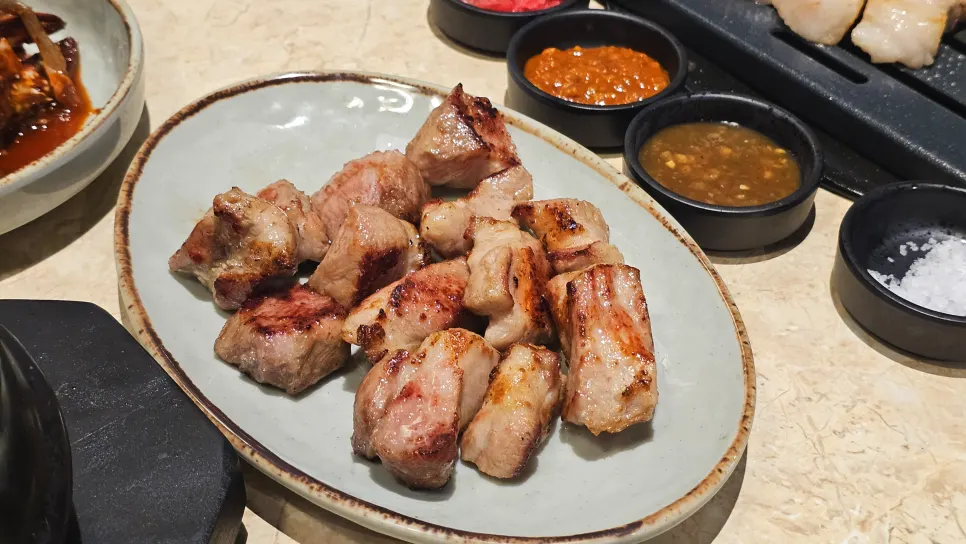 Staff grilling pork over charcoal for the table