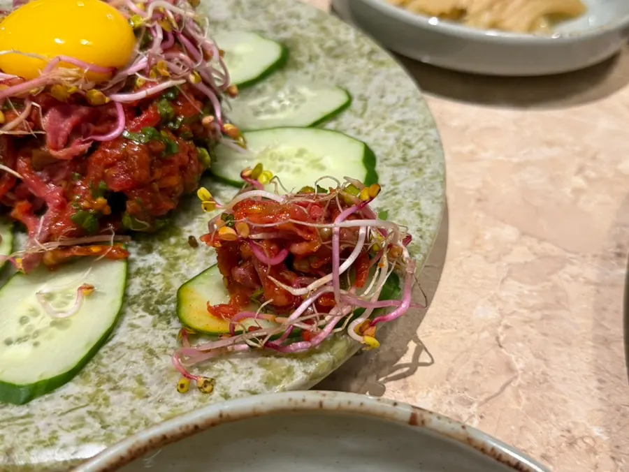 A bite of minari beef tartare with cucumber