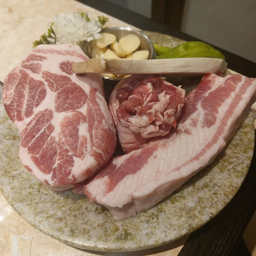 Raw plate of snowflake pork neck, rib pork belly, and hanger meat