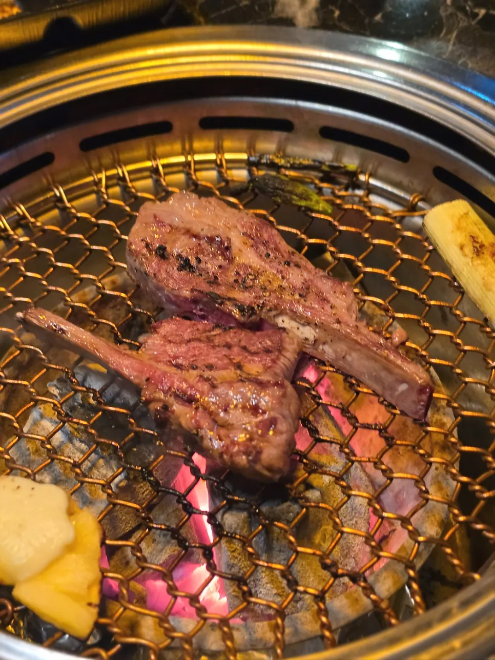 Lamb rack grilling to a golden brown over charcoal