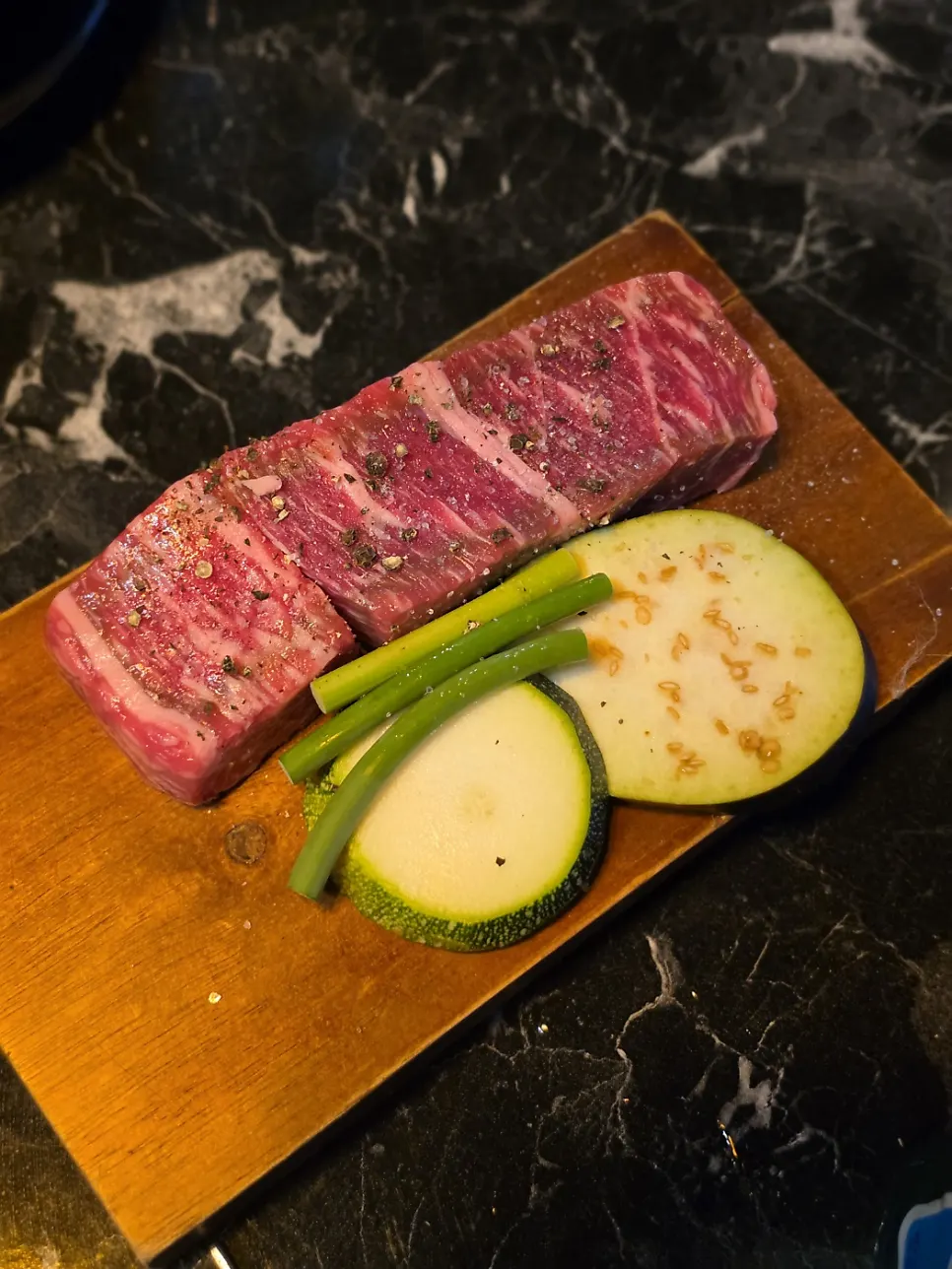 A shot glass of soju alongside the meat