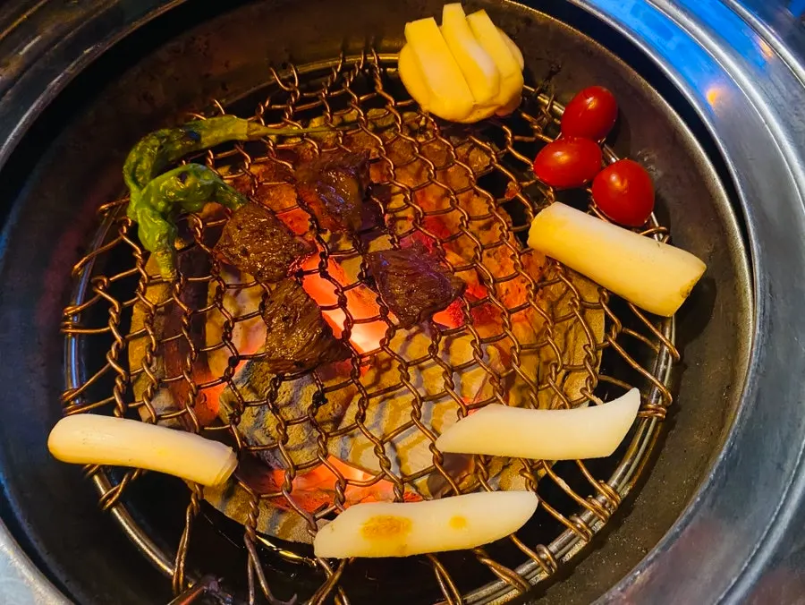 Trimmed beef grilling over charcoal