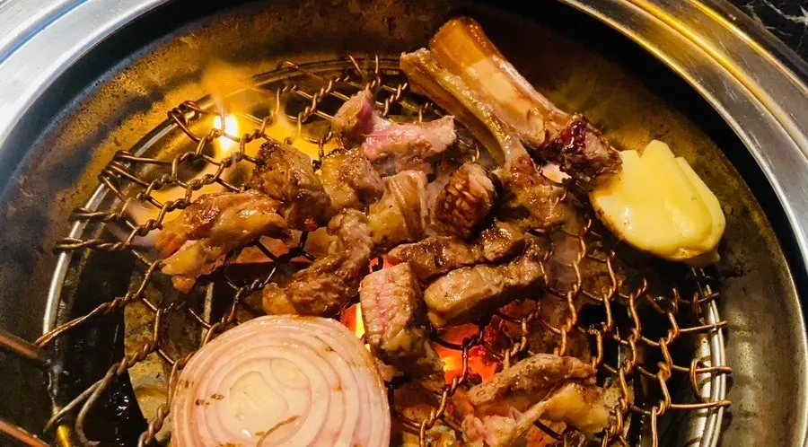 Lamb ribs with bone being trimmed on the grill