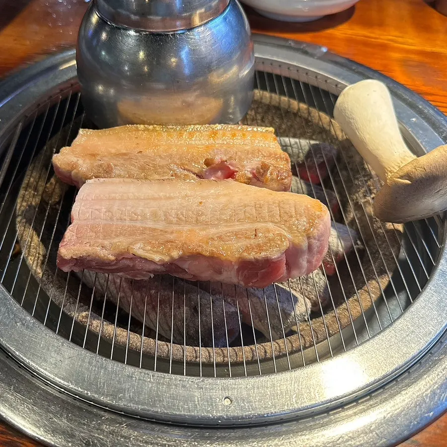 Staff grilling ogyeopsal at Yuk Tongnyeong Gyodae Branch