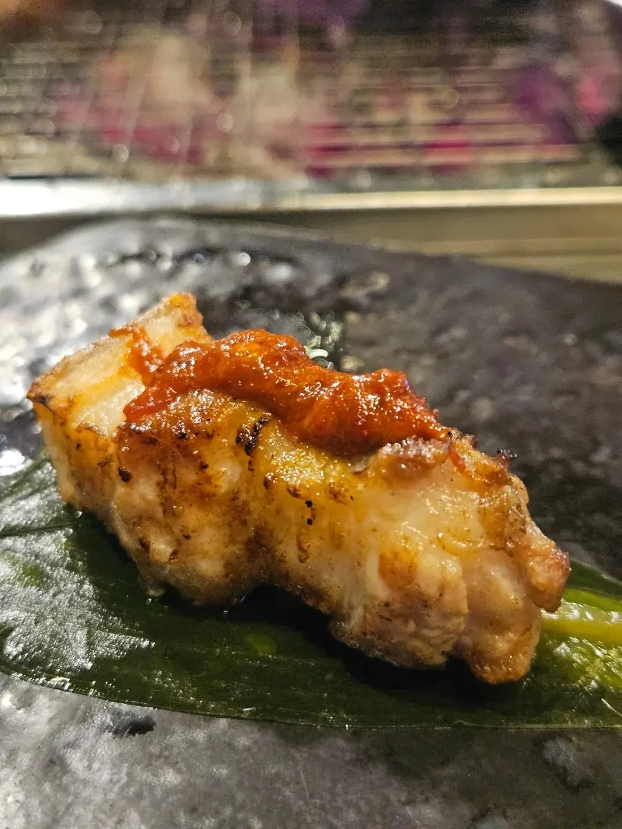 カタクチイワシの塩辛をつけて食べる厚切りオギョプサル一切れ