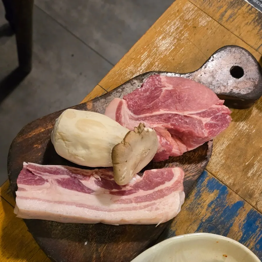 Black pork yukgyeopsal grilling over charcoal