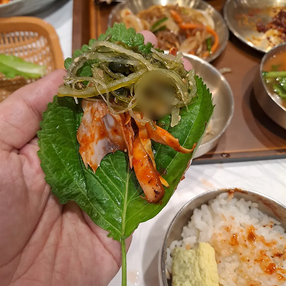 A bite of grilled mackerel placed on a lettuce wrap