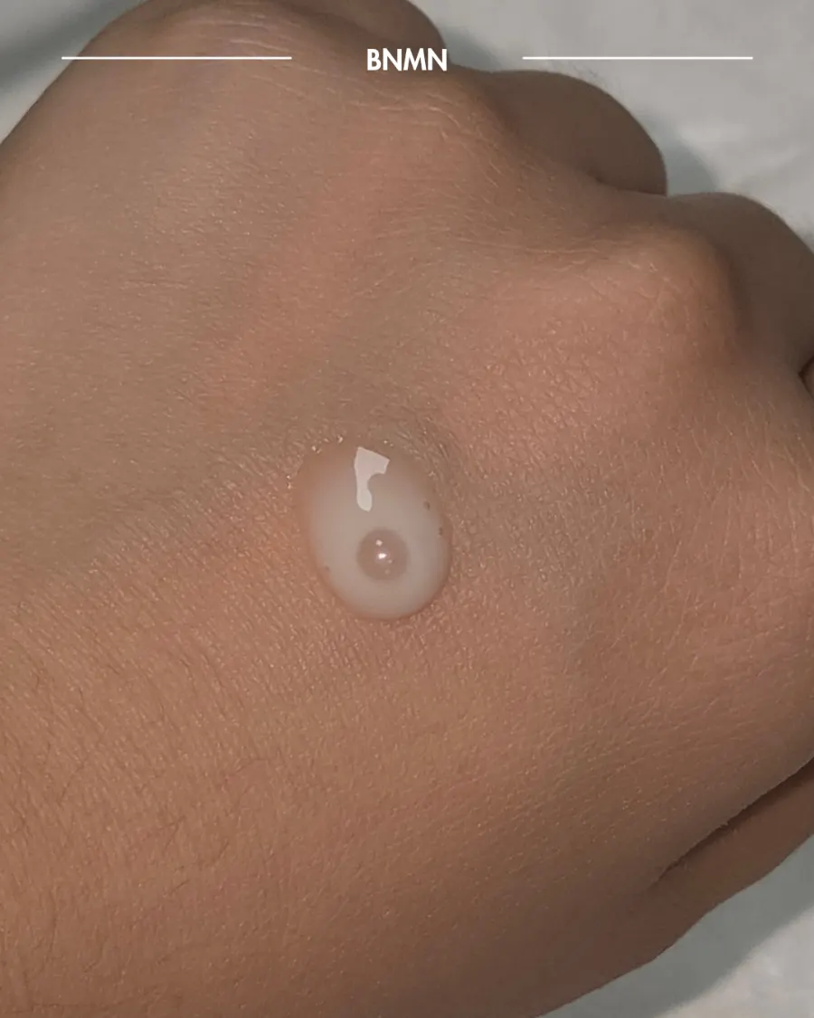 Milky-colored ampoule texture dispensed onto the back of a hand