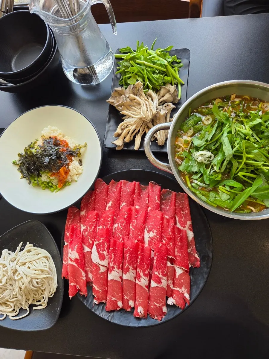 Minari and mushrooms piled on red broth