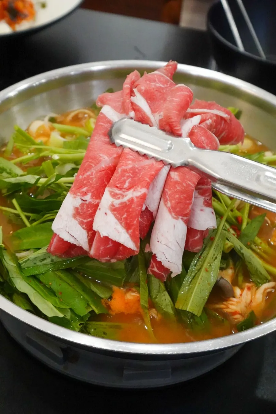 Pot of red broth with shabu-shabu ingredients