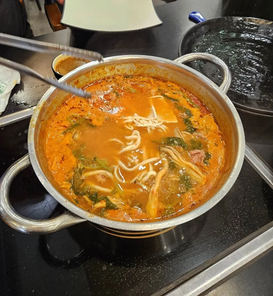 Kalguksu noodles cooking in the deepened red broth