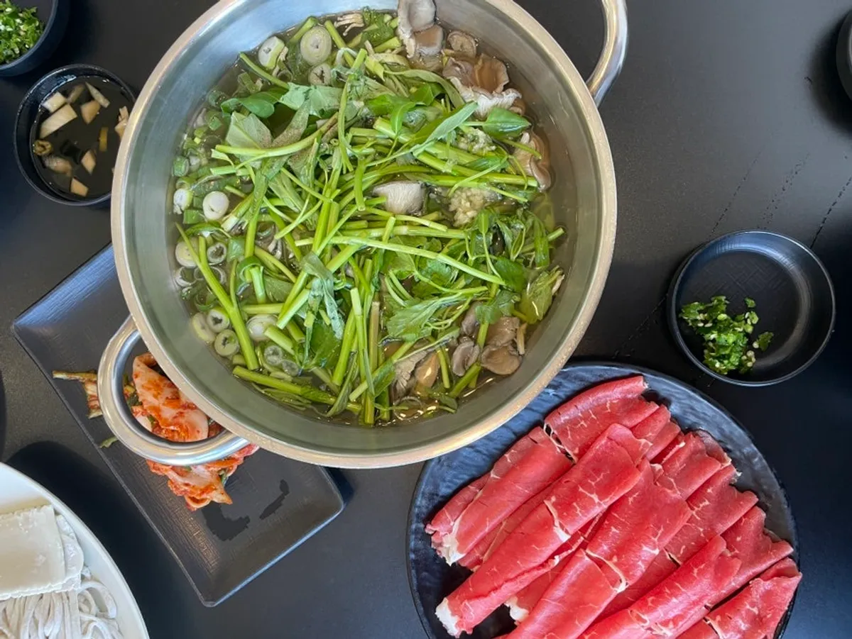 White broth shabu-kalguksu spread with mushrooms and minari