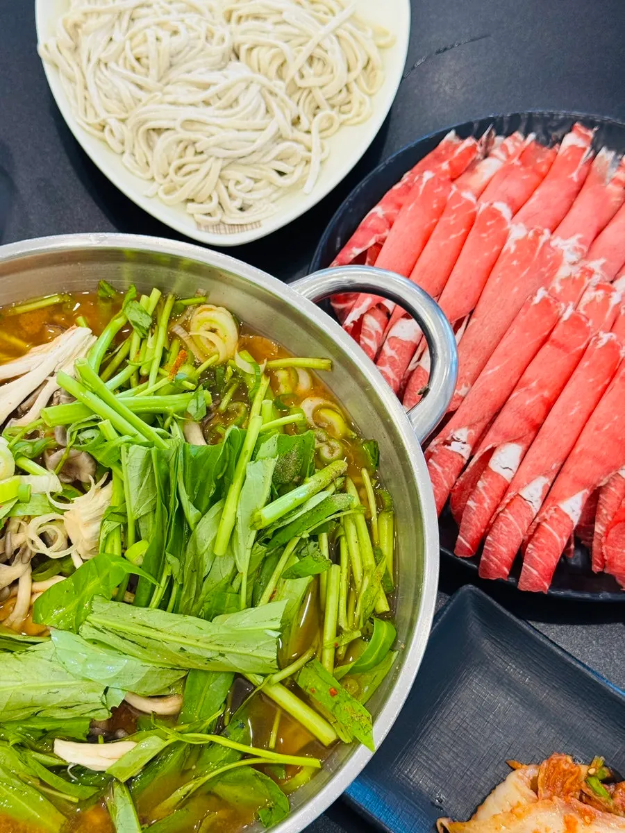 Meat and kong-simchae being blanched in red broth