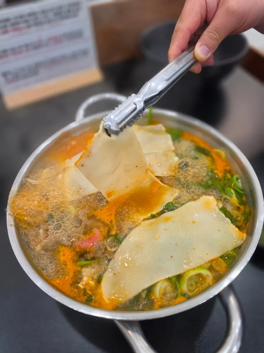 Flat kalguksu noodles cooking in the broth