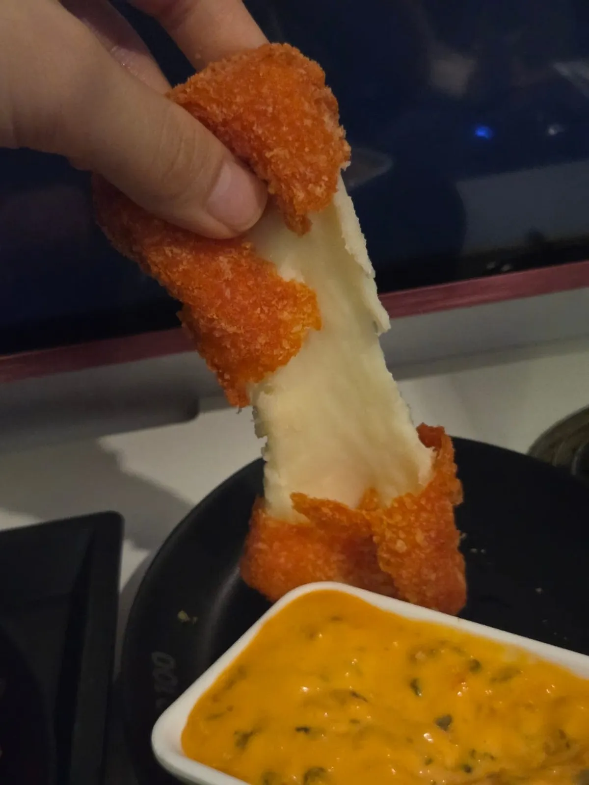 Two cheese sticks served with dipping sauce